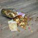 A glass jar with euro coins and banknotes spilled on a wooden surface, representing finance and savings.