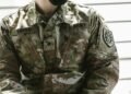 Detailed view of a U.S. Army soldier's camouflage uniform with insignia and name tags visible.