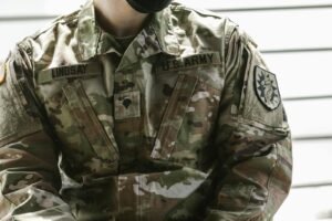 Detailed view of a U.S. Army soldier's camouflage uniform with insignia and name tags visible.