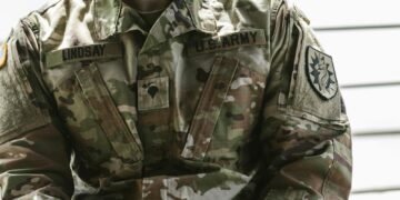 Detailed view of a U.S. Army soldier's camouflage uniform with insignia and name tags visible.