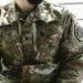 Detailed view of a U.S. Army soldier's camouflage uniform with insignia and name tags visible.