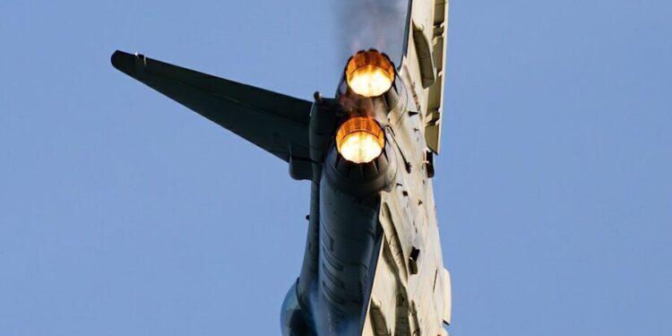 a fighter jet flying through a blue sky