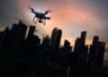 silhouette of quadcopter drone hovering near the city