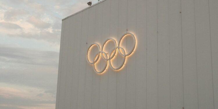 White building with illuminated olympic rings symbol